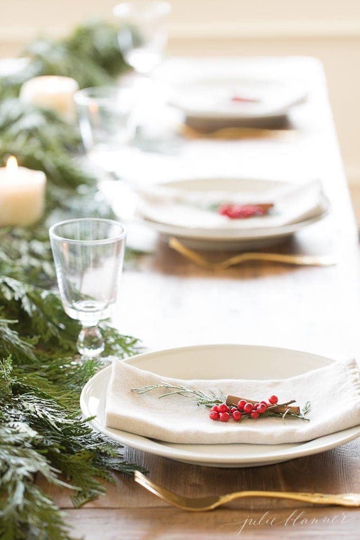 A festive table setting adorned with a garland of holly and pine cones.