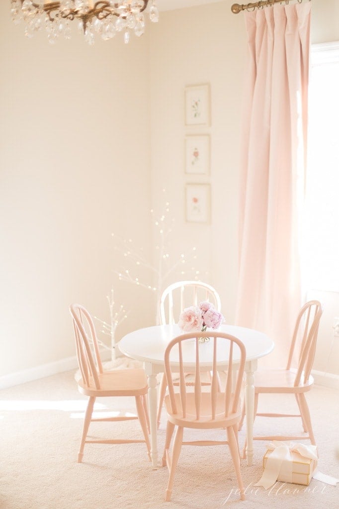 A girl's bedroom with pink blackout curtains and a small table and chairs.