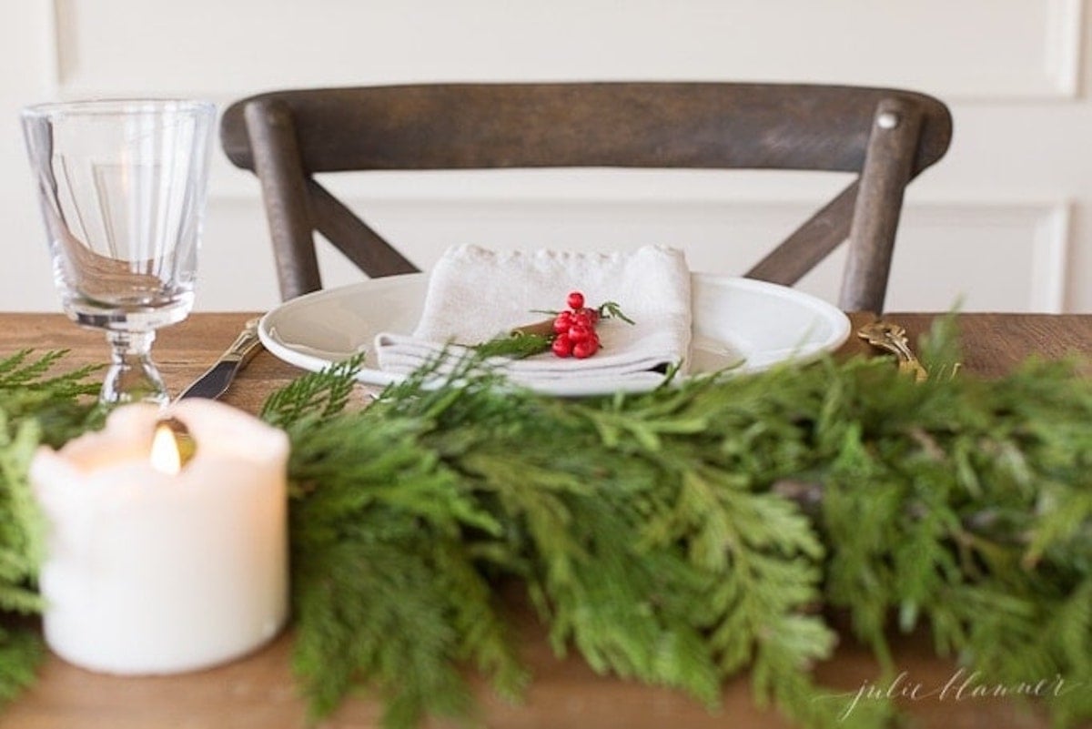 A Christmas table setting adorned with a candle and garland.