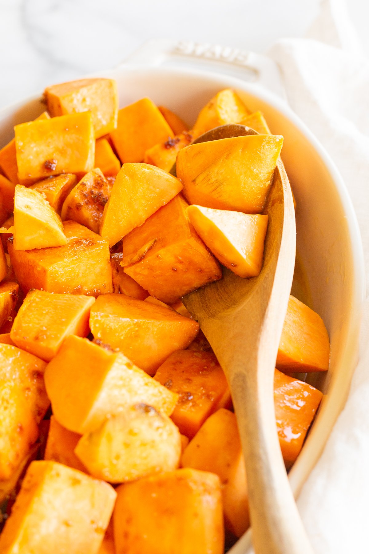 A white oval baking dish filled with roasted sweet potatoes.