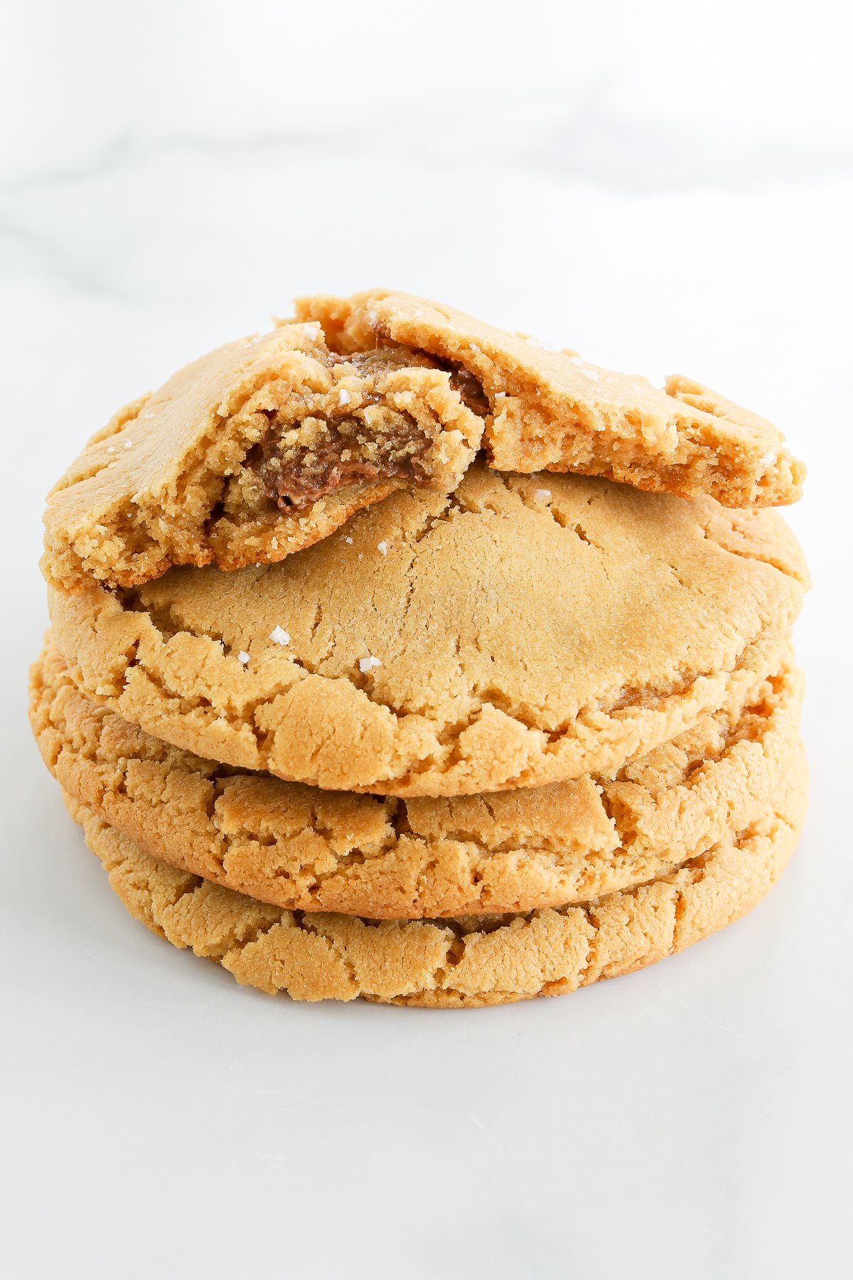 A stack of peanut butter stuffed cookies with a bite taken out of them.