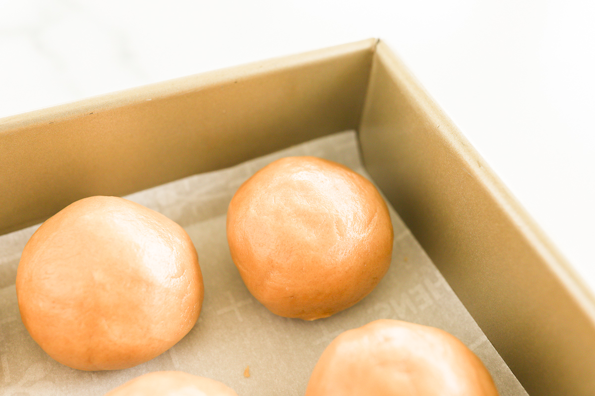A box of orange doughnuts, stuffed with peanut butter, in a white box.