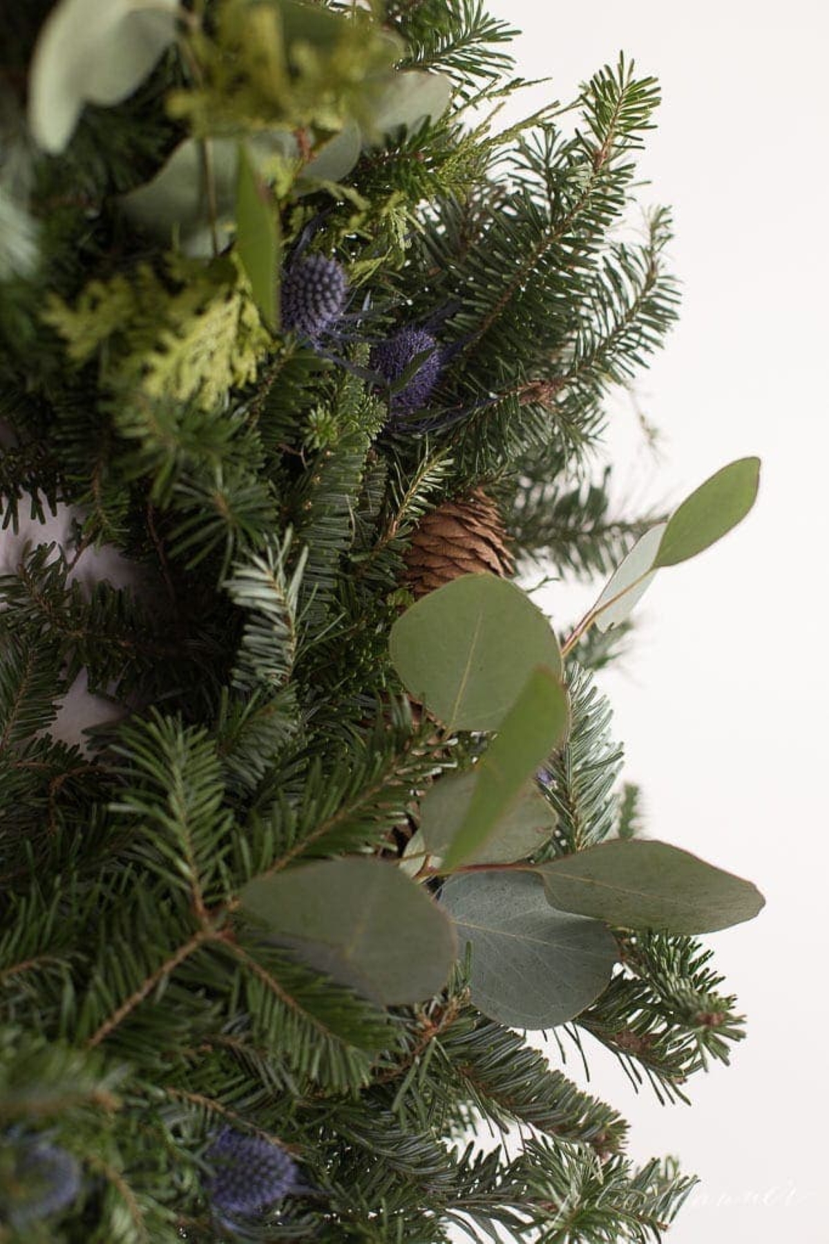 Fresh greenery added to a basic Christmas wreath for an upgraded Christmas wreath decorating idea