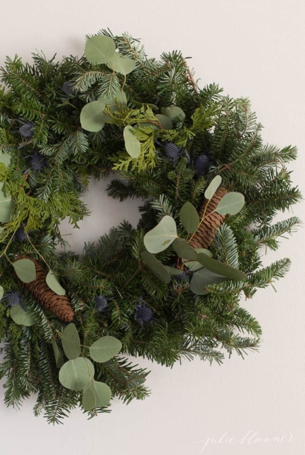 Fresh greenery added to a basic Christmas wreath for an upgraded Christmas wreath decorating idea