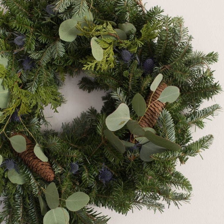 Fresh greenery added to a basic Christmas wreath for an upgraded Christmas wreath decorating idea
