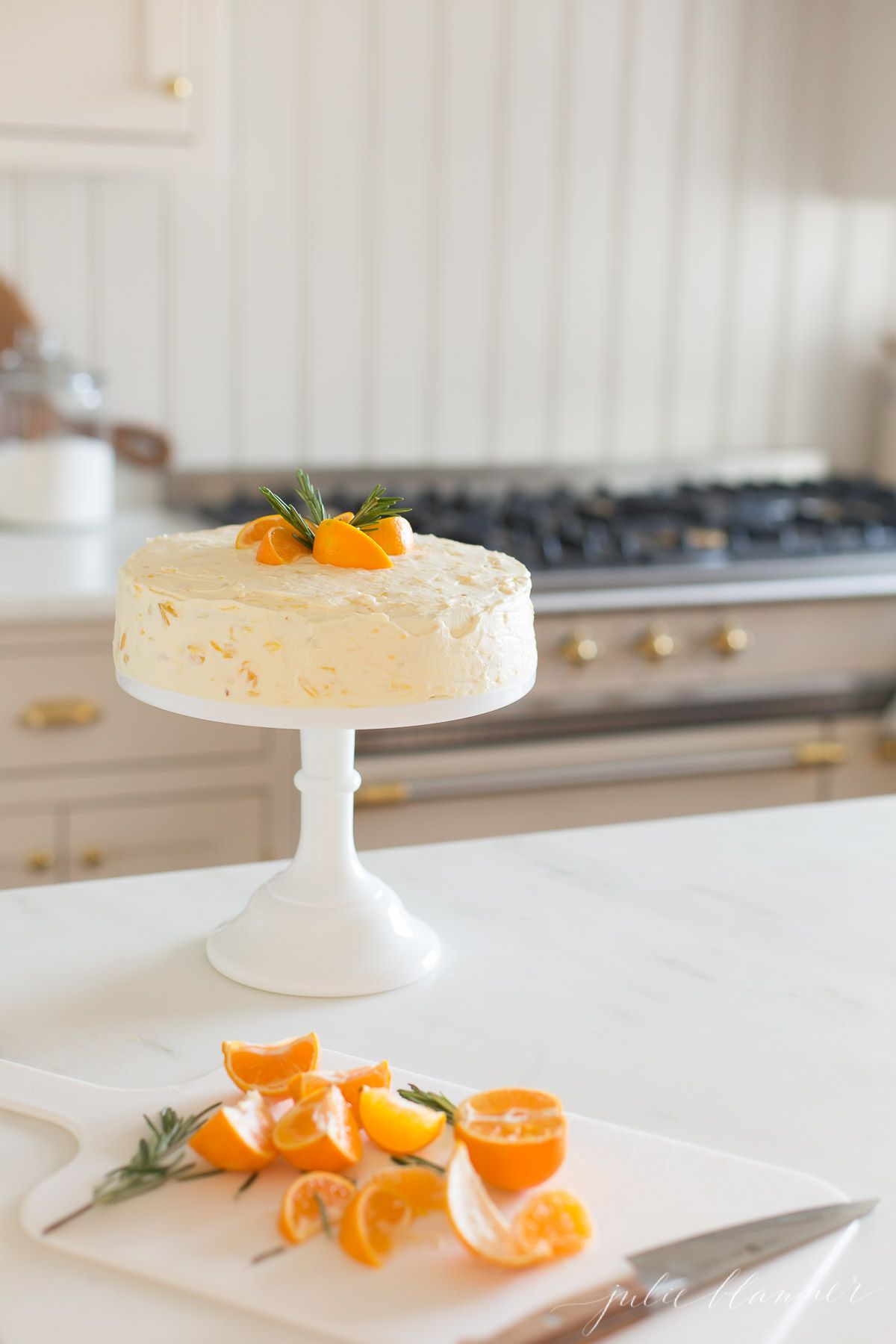 Sliced mandarin oranges and rosemary sprigs on top of a mandarin orange cake.