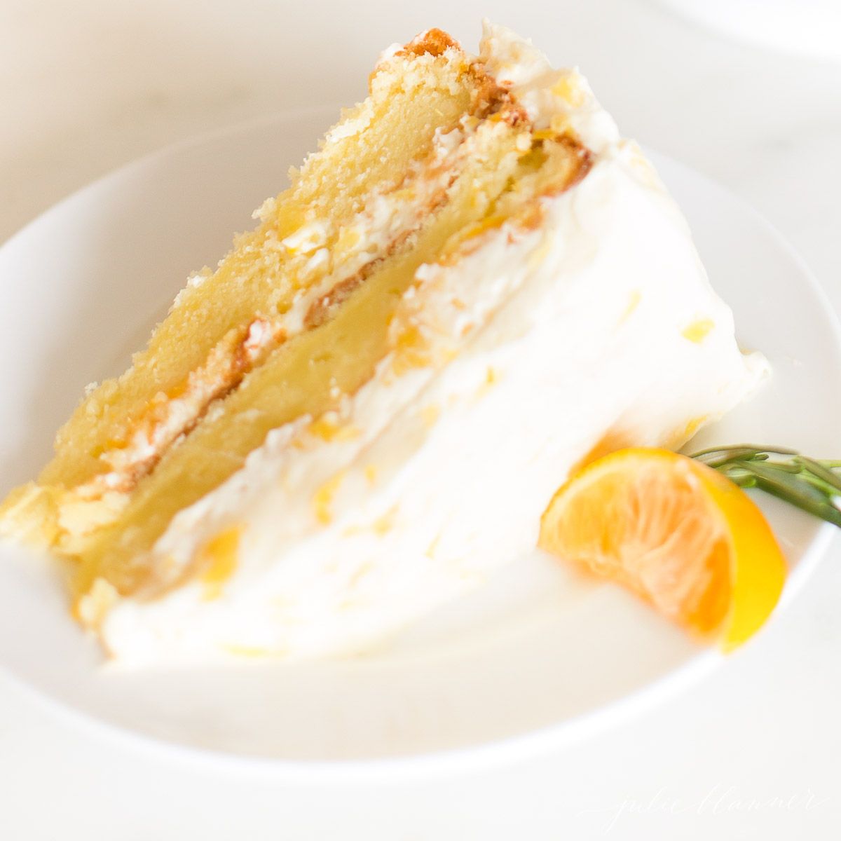 A slice of mandarin orange cake on a white plate.