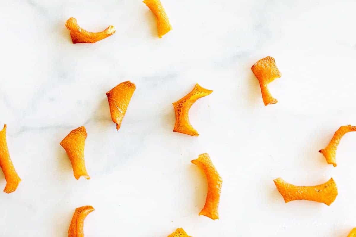 Dried orange peels spread out on a white marble surface.