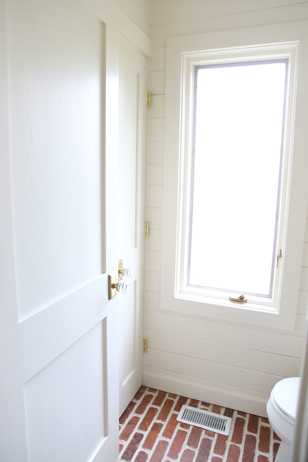 A bathroom painted in Benjamin Moore Navajo White, with a toilet and a window.