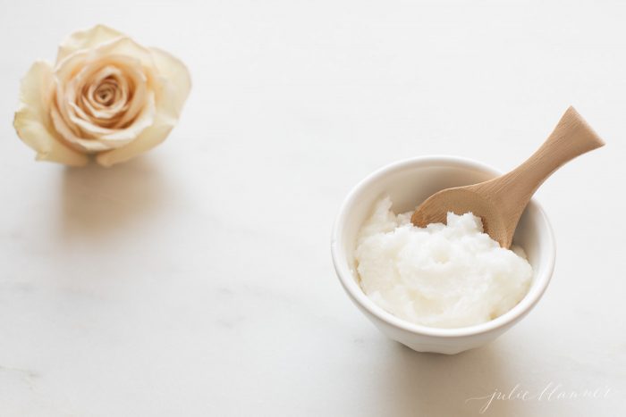 DIY Lip Scrub in a white bowl next to a rose