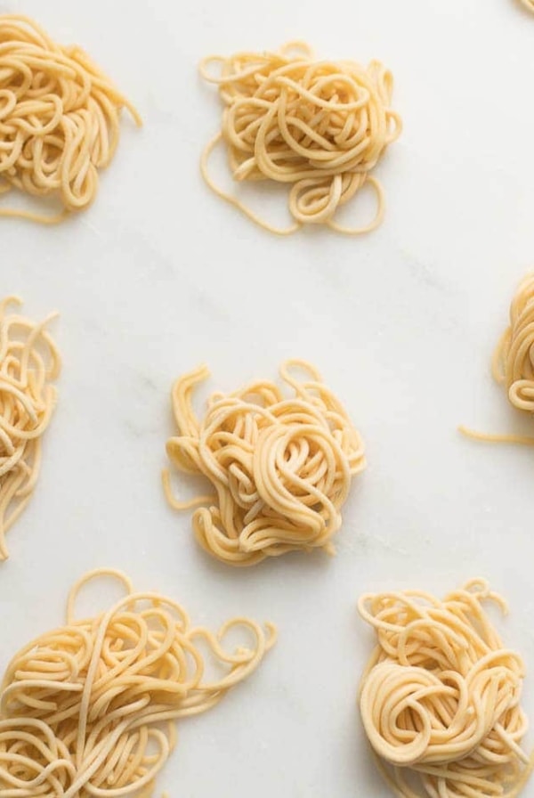 small swirls of spaghetti style egg noodles on a marble countertop
