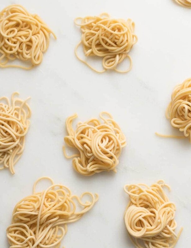 small swirls of spaghetti style egg noodles on a marble countertop