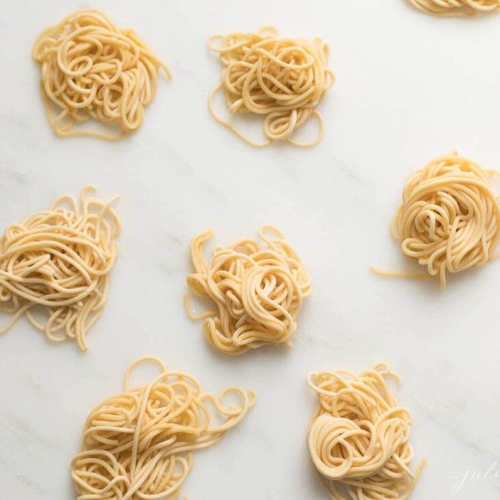 small swirls of spaghetti style egg noodles on a marble countertop