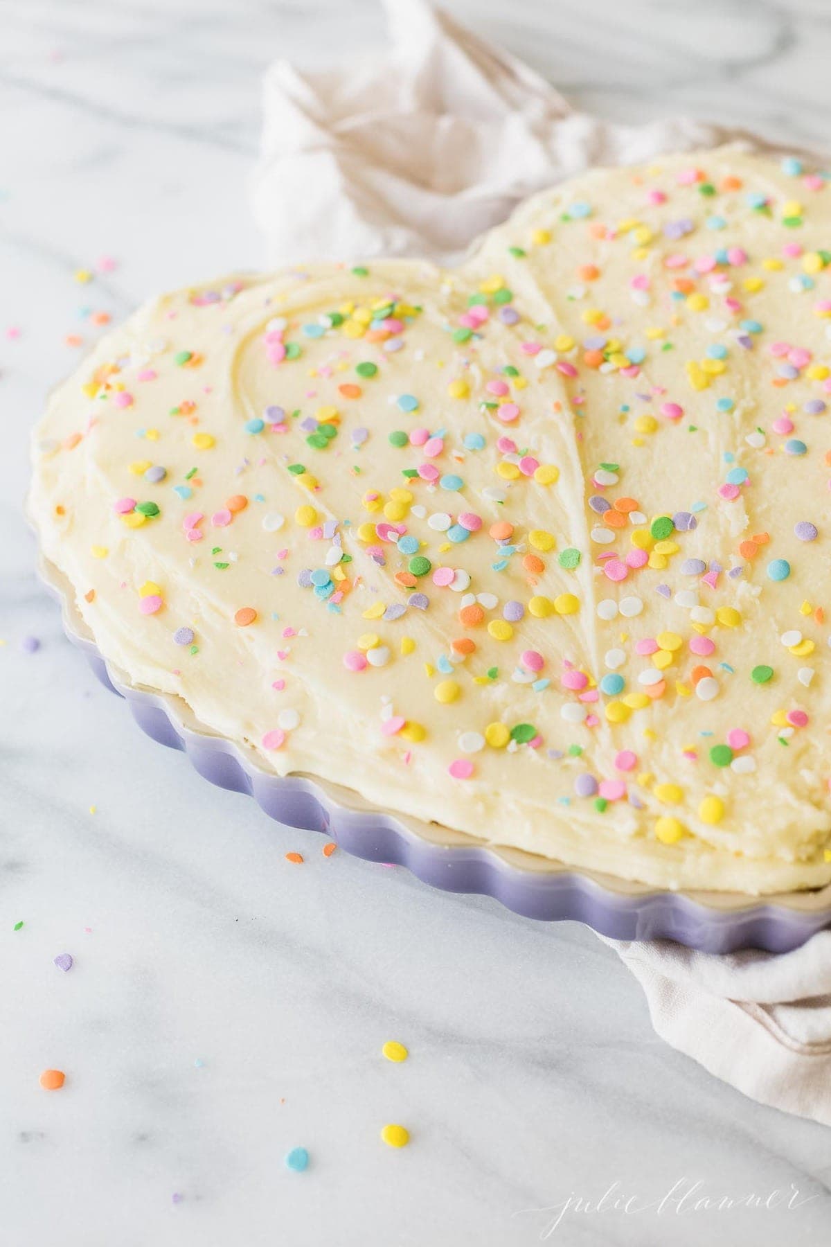 A frosted sugar cookie cake in a heart shaped pan