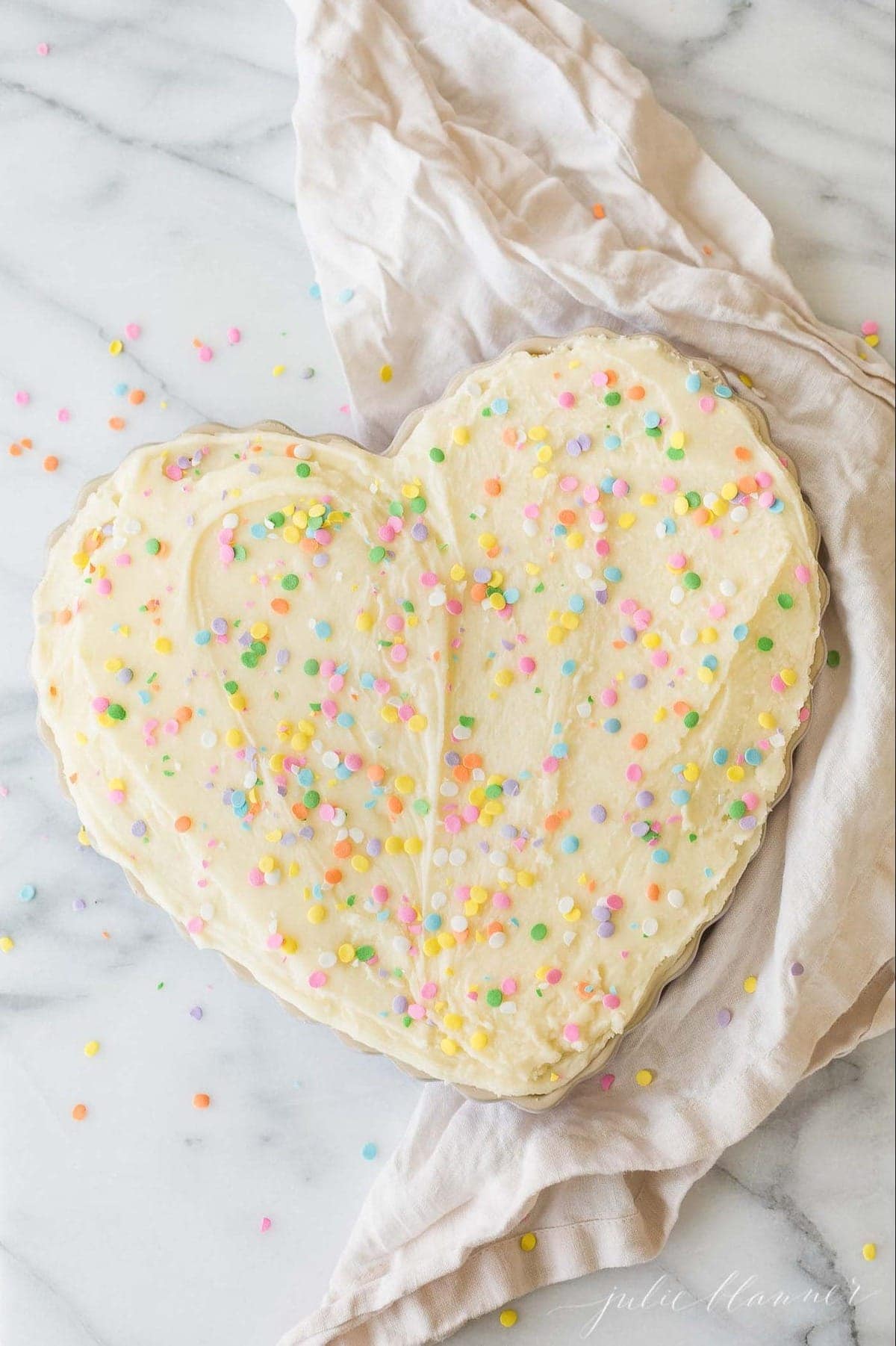 A decorated heart shaped cake on a marble work surface