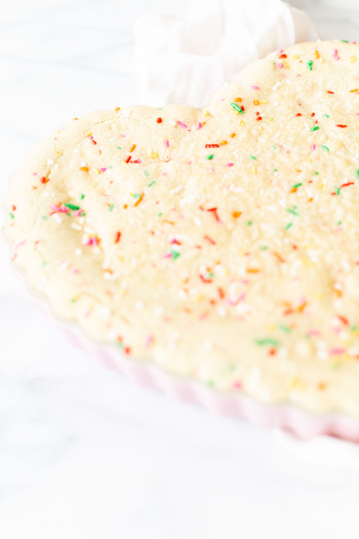 A funfetti cookie cake baked into a heart shaped pan.