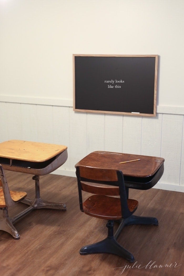 A minimalist living inspired basement for kids, with vintage school desks, a chalkboard and wood floors.