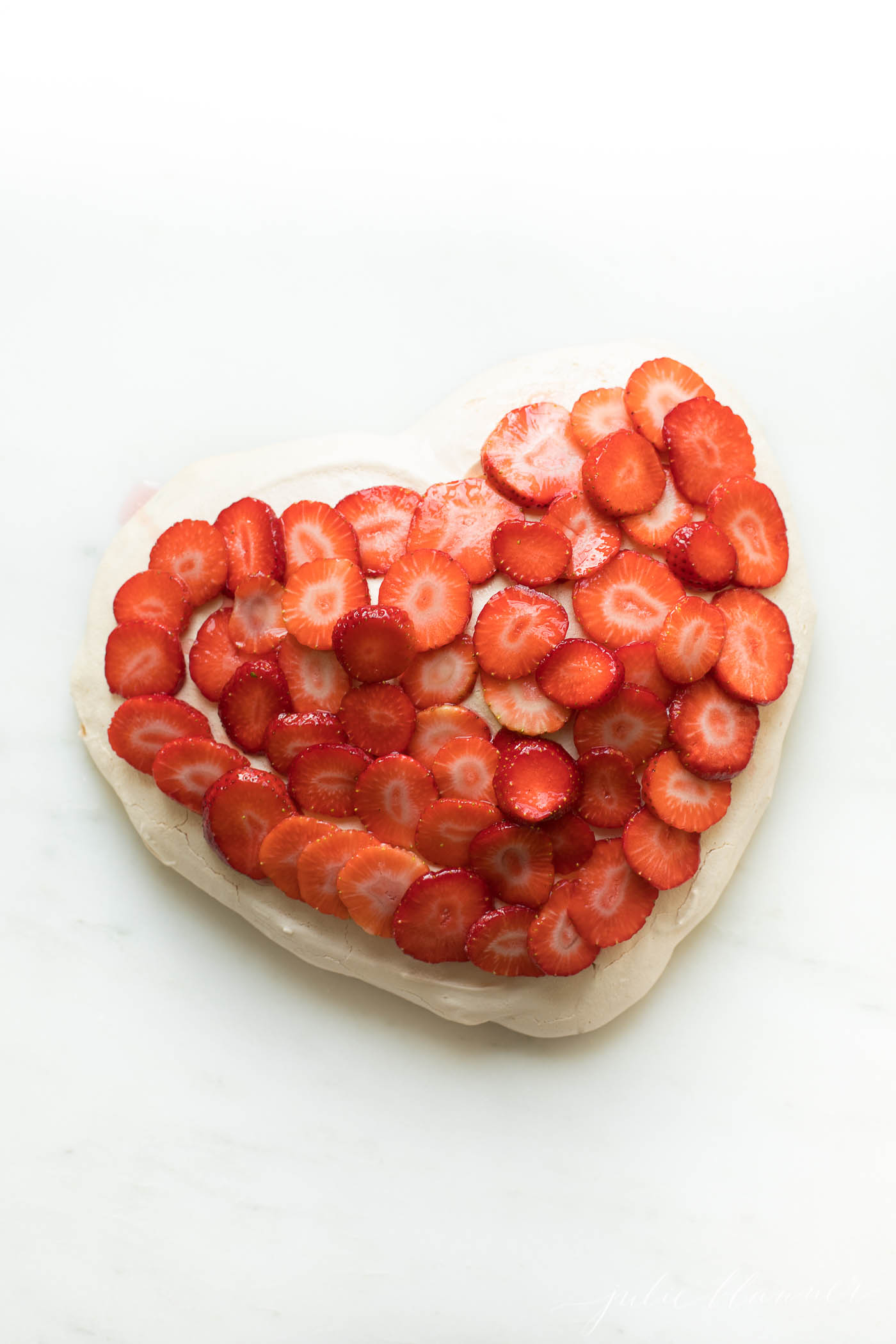 easy meringue recipe in the shape of a heart, topped with strawberries 
