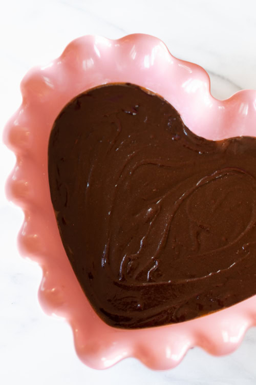 Heart-shaped brookie dessert in a pink scalloped dish on a marble surface.