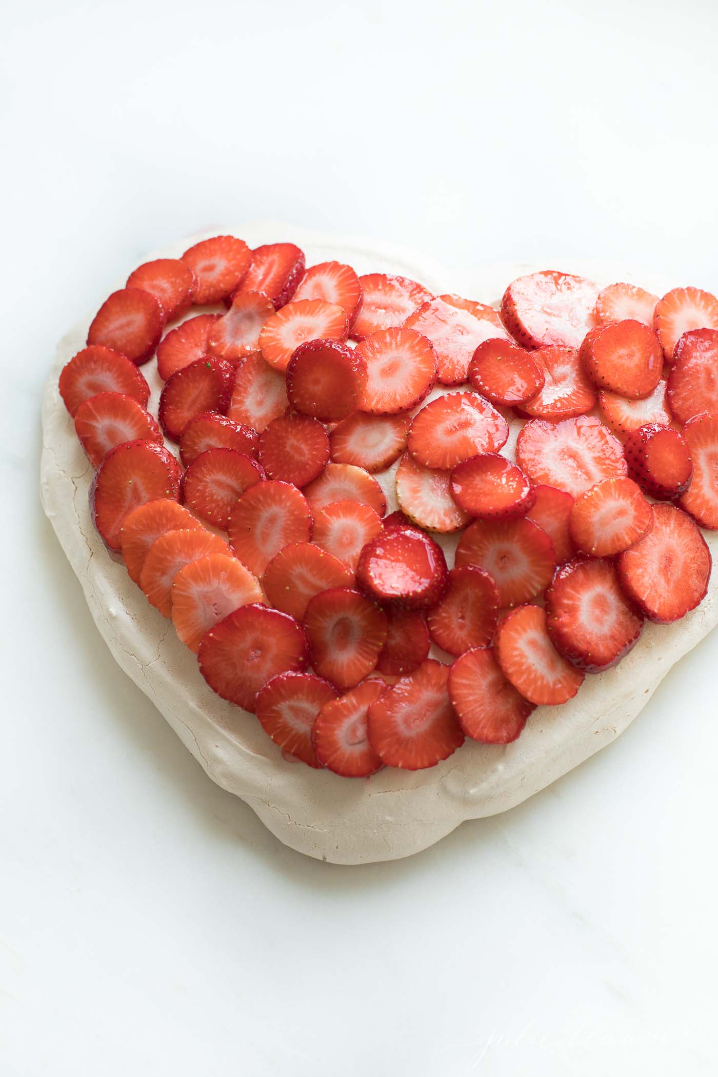 easy meringue recipe in the shape of a heart, topped with strawberries