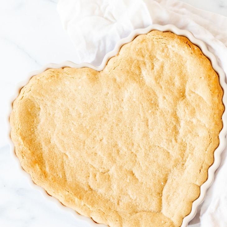 A heart shaped peanut butter cookie cake on a marble countertop.