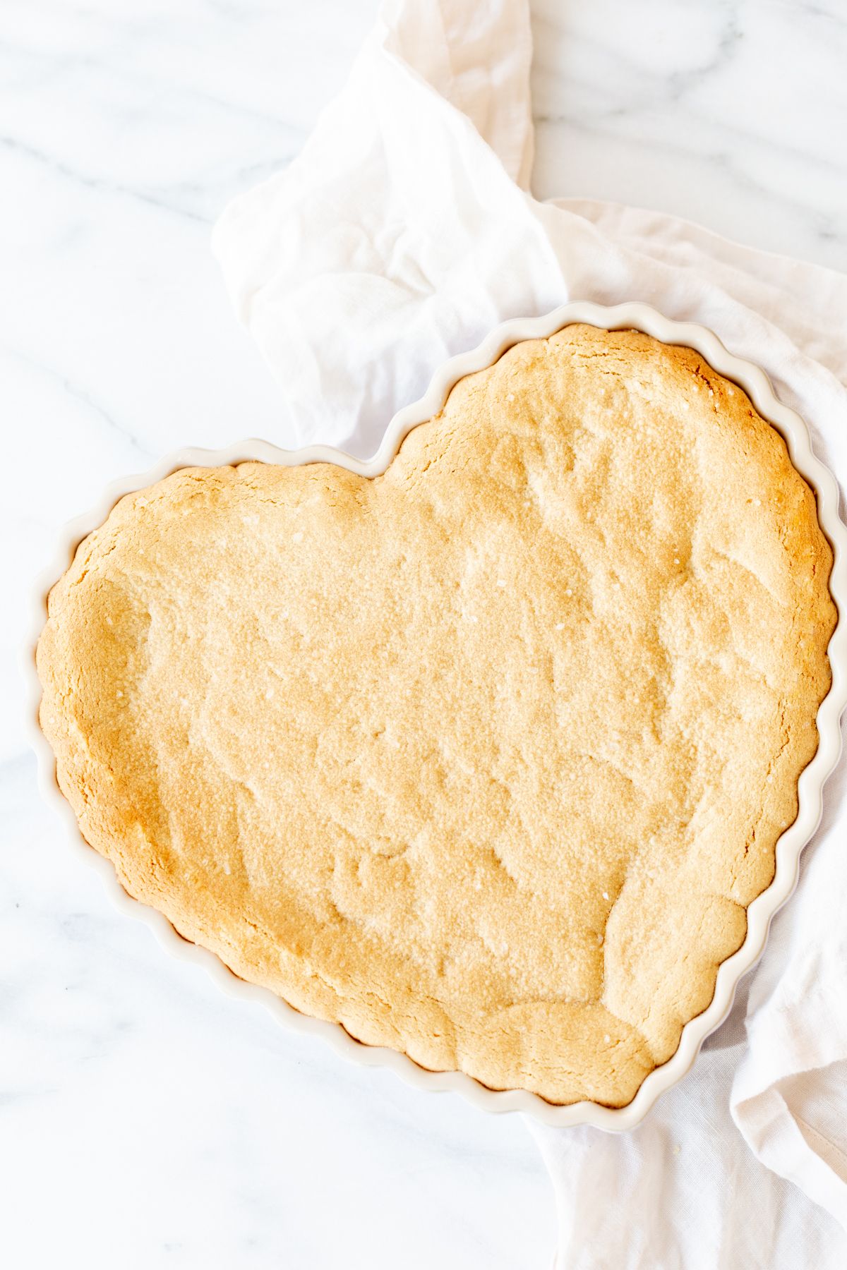 A heart shaped peanut butter cookie cake on a marble countertop.