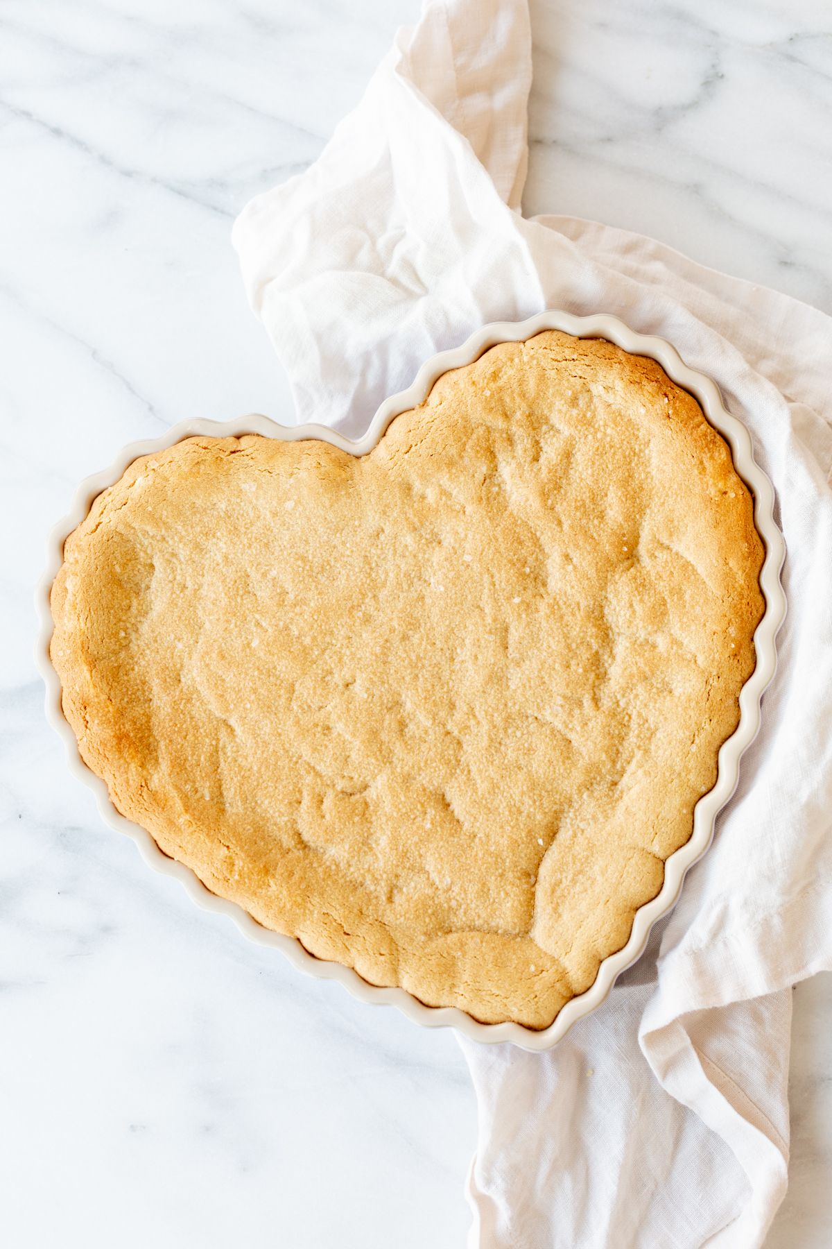 A heart shaped peanut butter cookie cake on a marble countertop.