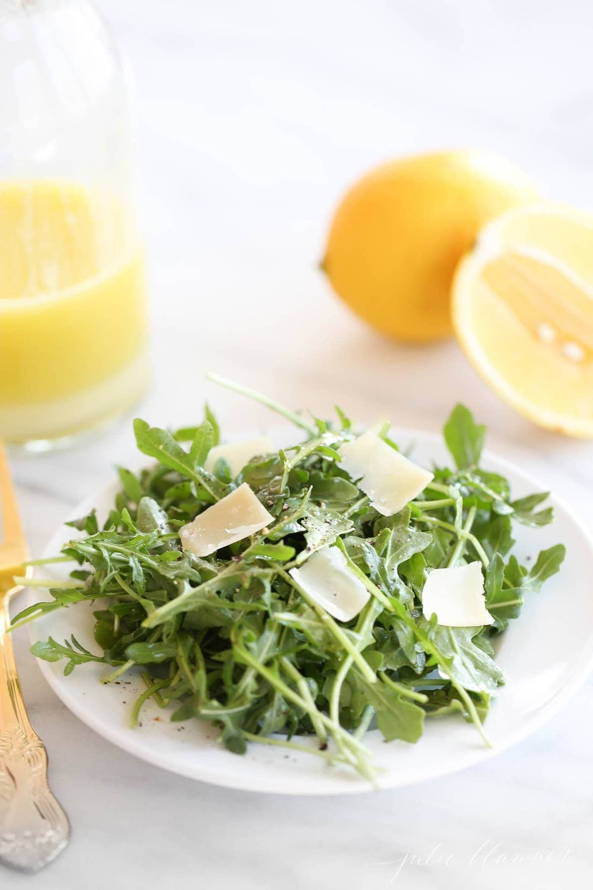 arugula salad recipe on white plate with parmesan and lemon vinaigrette