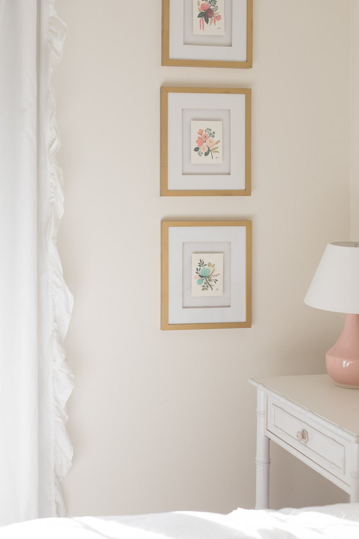 Gold framed art in a girl's white bedroom.