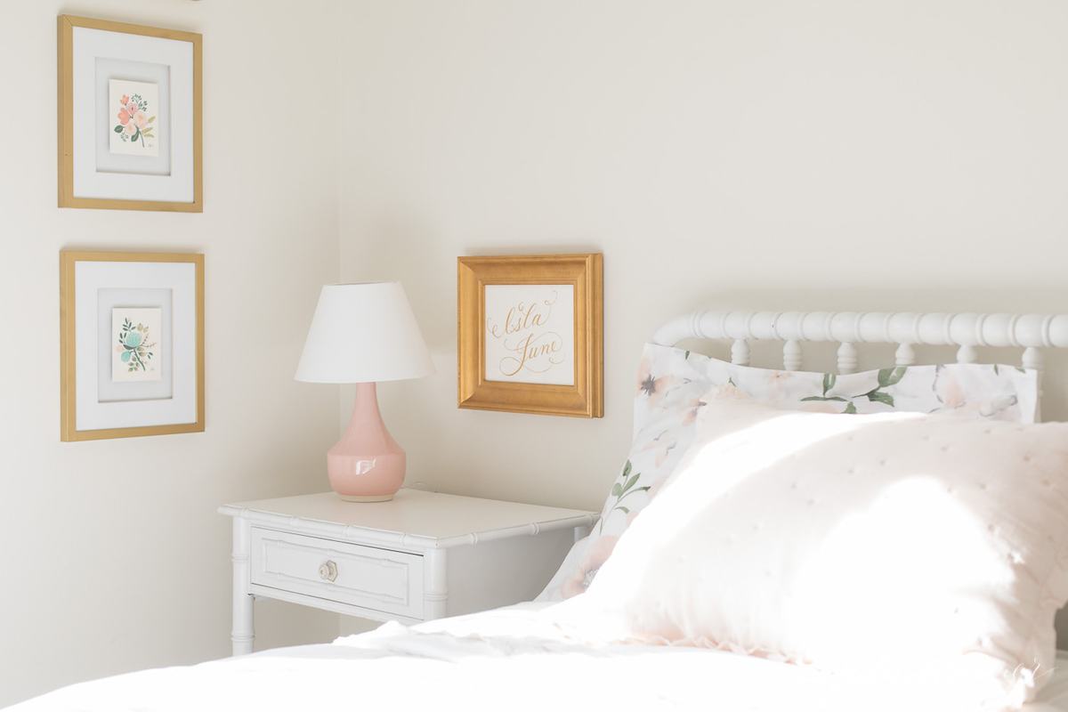 A white bedroom with light pink and gold accents. 