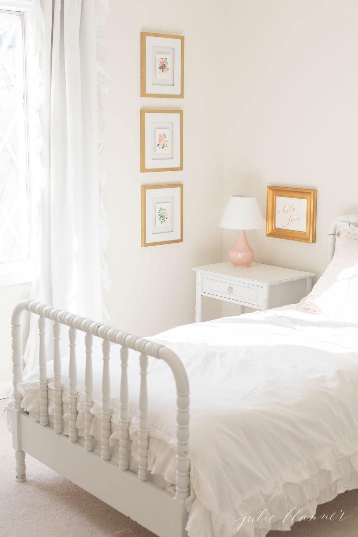 A white girl's bedroom with gold framed artwork.