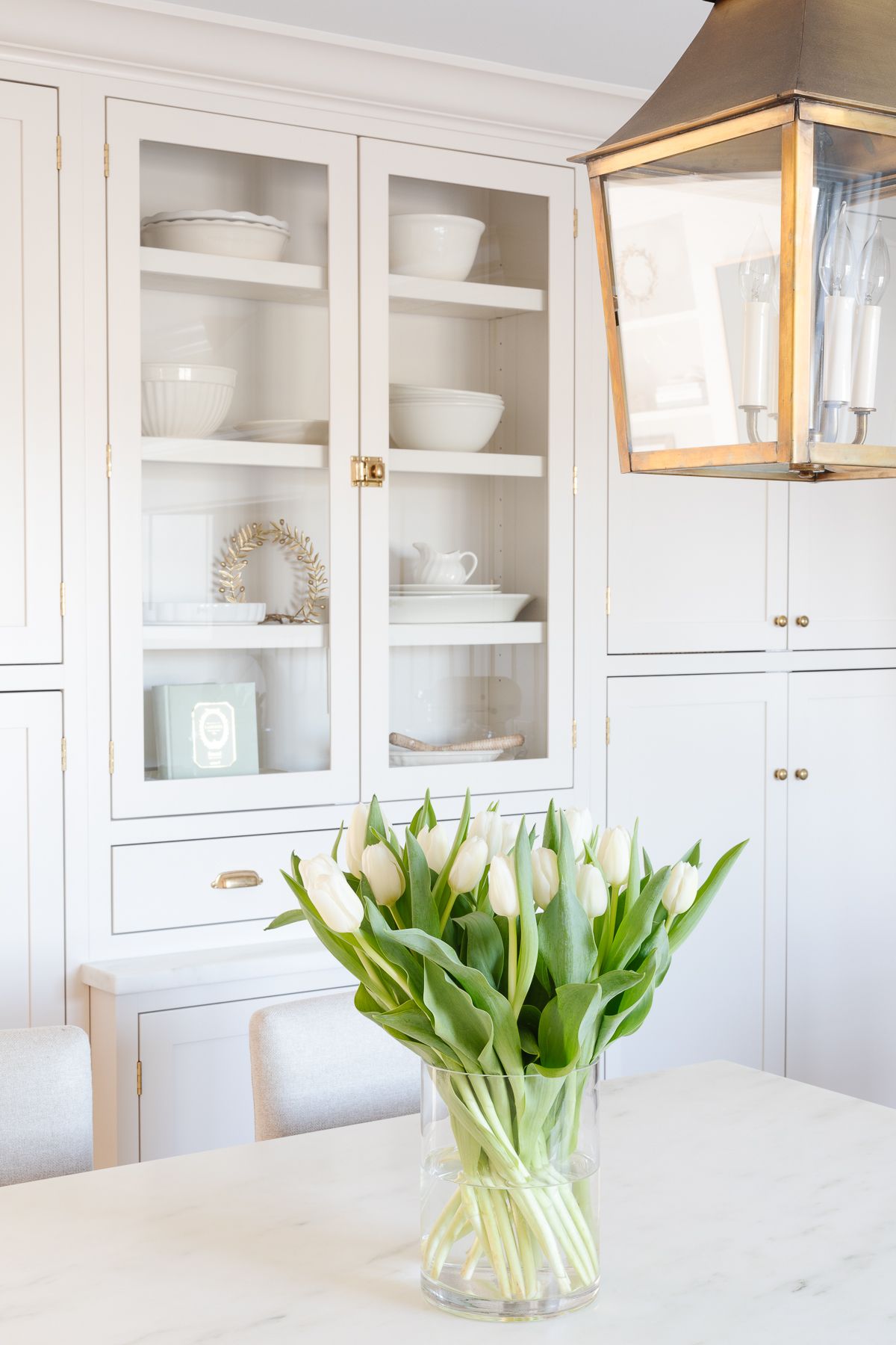 A white tulip arrangement on a marble island countertop.