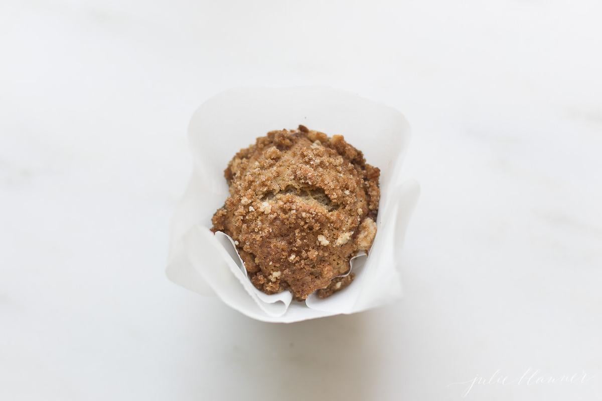 overhead view of a banana muffin with crumb topping in parchment liner