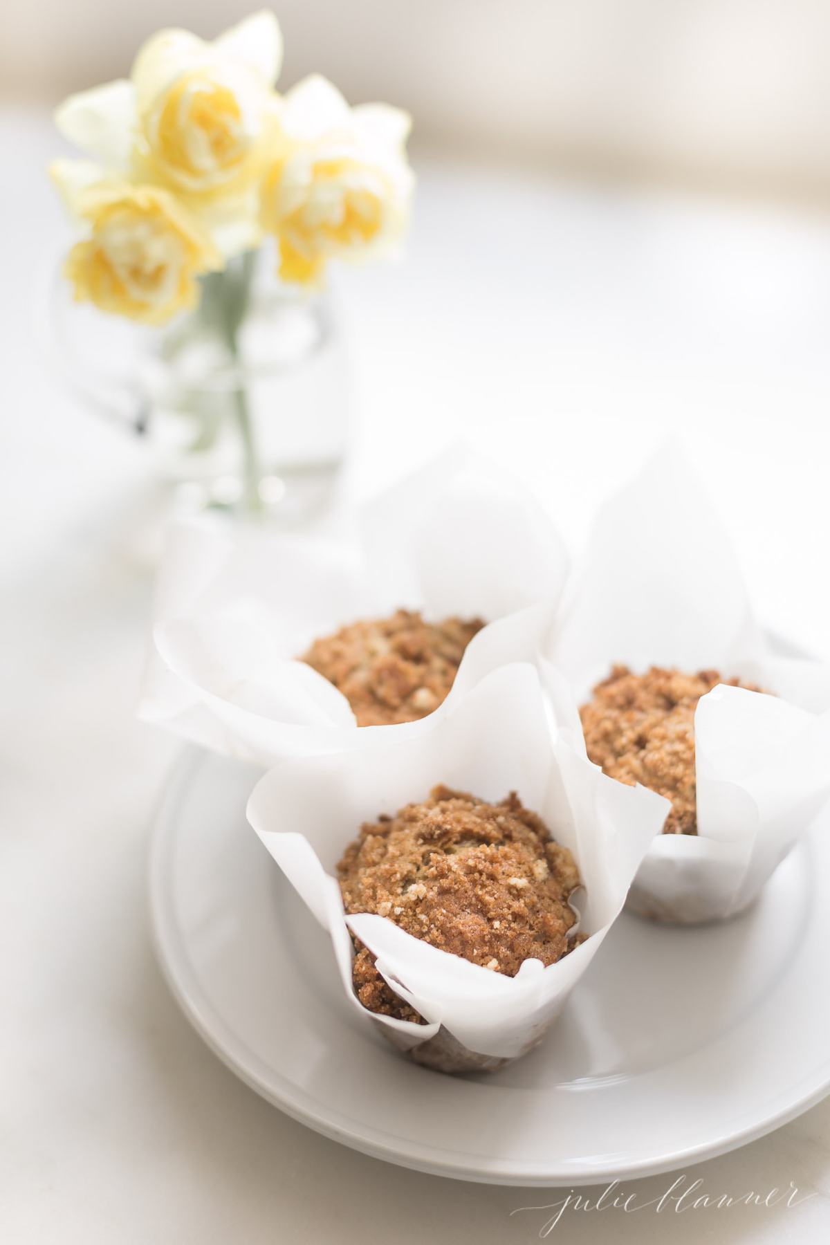 3 banana muffins on a plate with yellow flowers