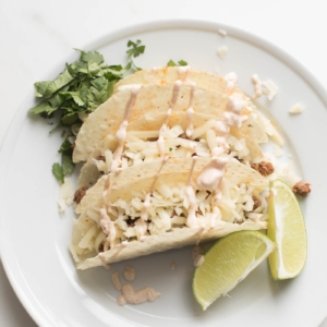 best beef taco recipe on white plate with lime wedges and cilantro