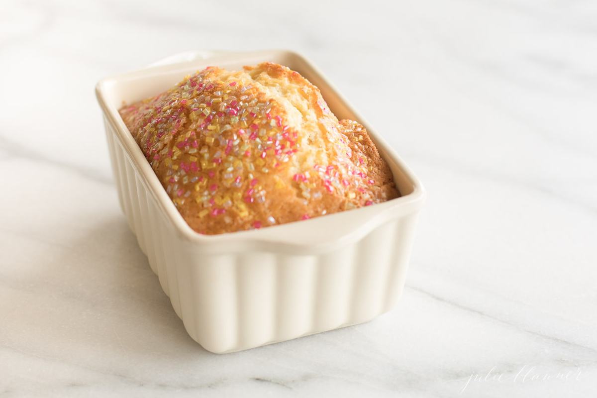 A funfetti loaf in a white ceramic loaf pan on a marble surface