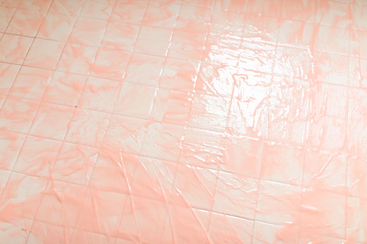 Person applying pink Citrus Strip onto old bathroom tiles.