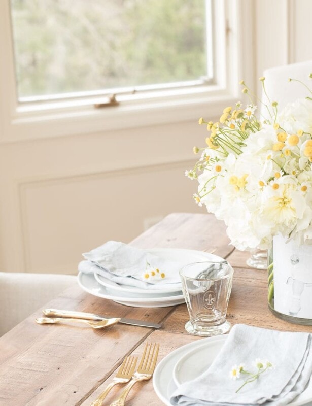 A mother's day decor idea of a DIY photo vase filled with flowers on a table set for brunch.