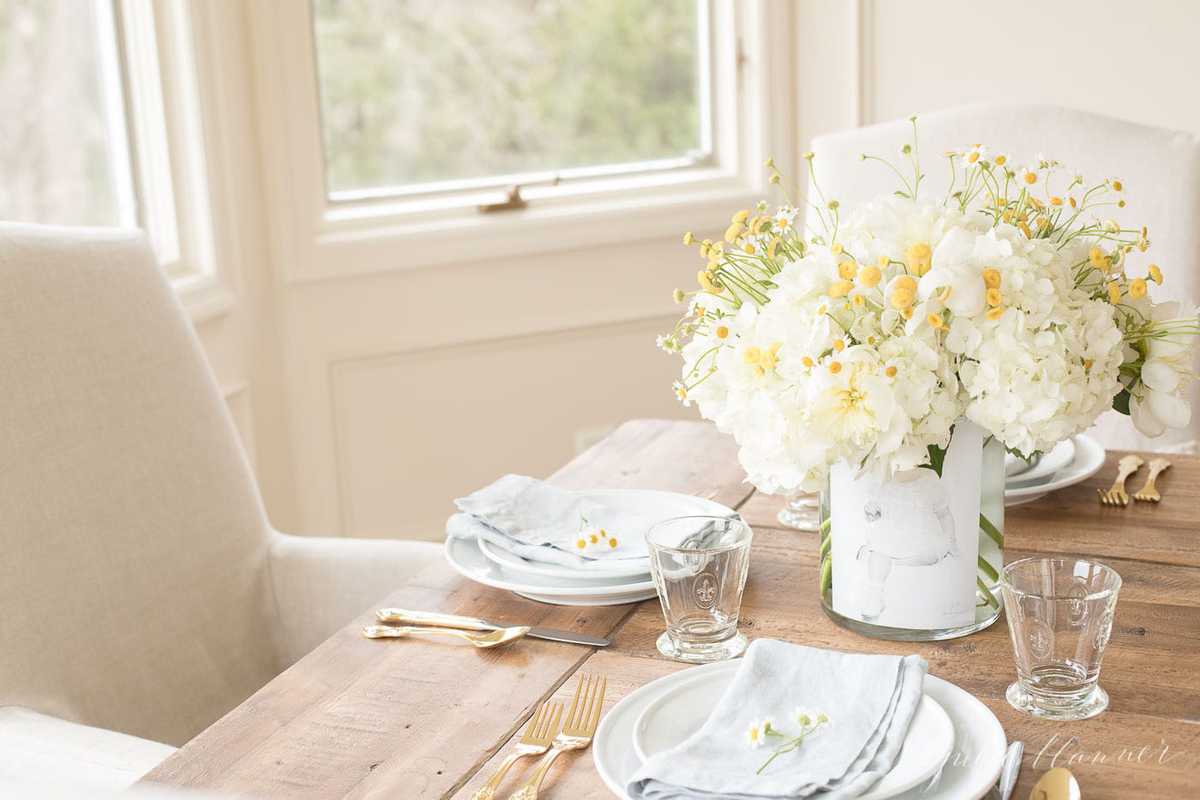 A mother's day decor idea of a DIY photo vase filled with flowers on a table set for brunch.