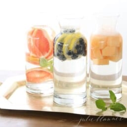 Three clear glass carafes full of fruit infused water.