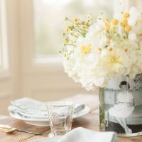 A table set with mother's day decorations of a simple vase of flowers with a vintage photo inside.