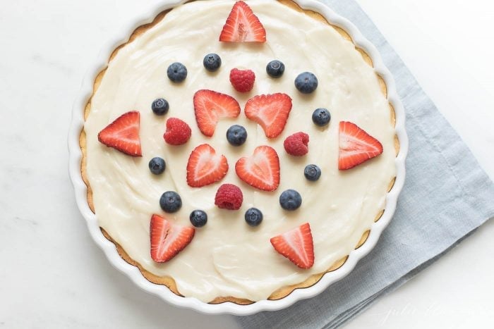 fruit pizza with cream cheese frosting decorated with strawberries and blueberries in a star shape
