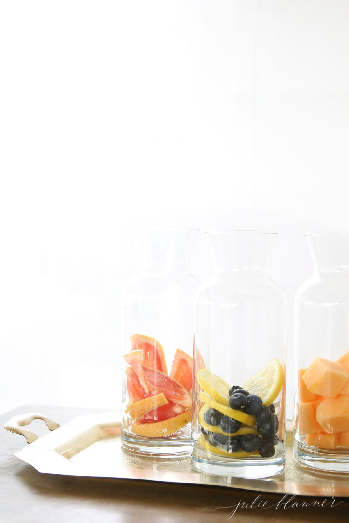 Three glass carafes full of fruit infused water recipes.