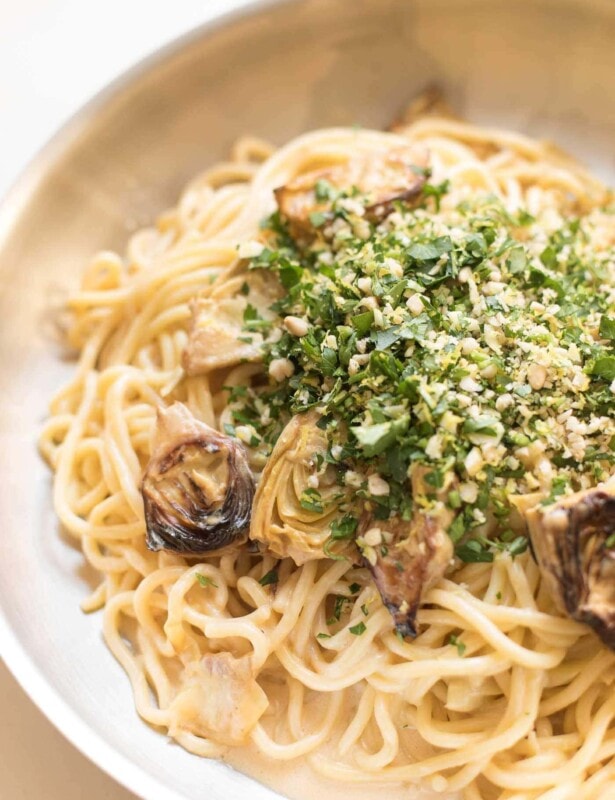 spaghetti in a skillet with artichokes topped with gremolata