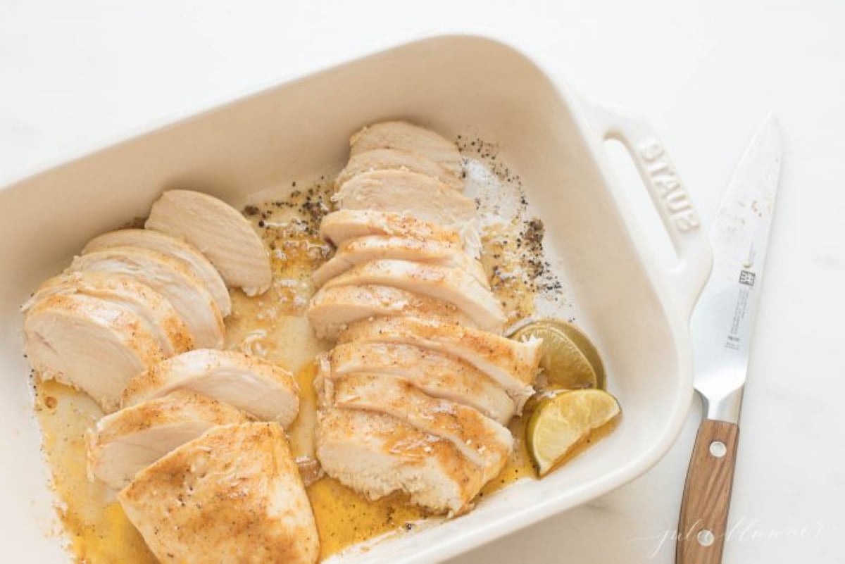 oven baked chicken breast sliced in a white baking dish.
