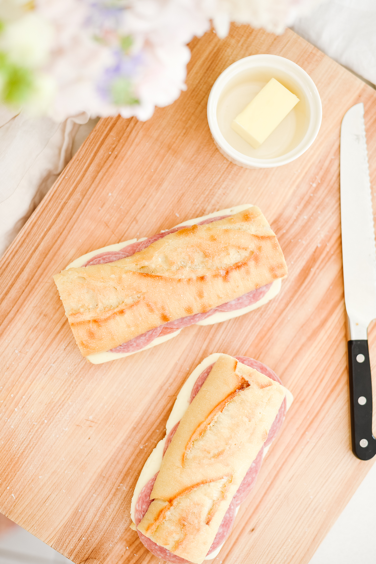 Picnic sandwiches on crusty bread, on a wooden cutting board with a knife to the side.