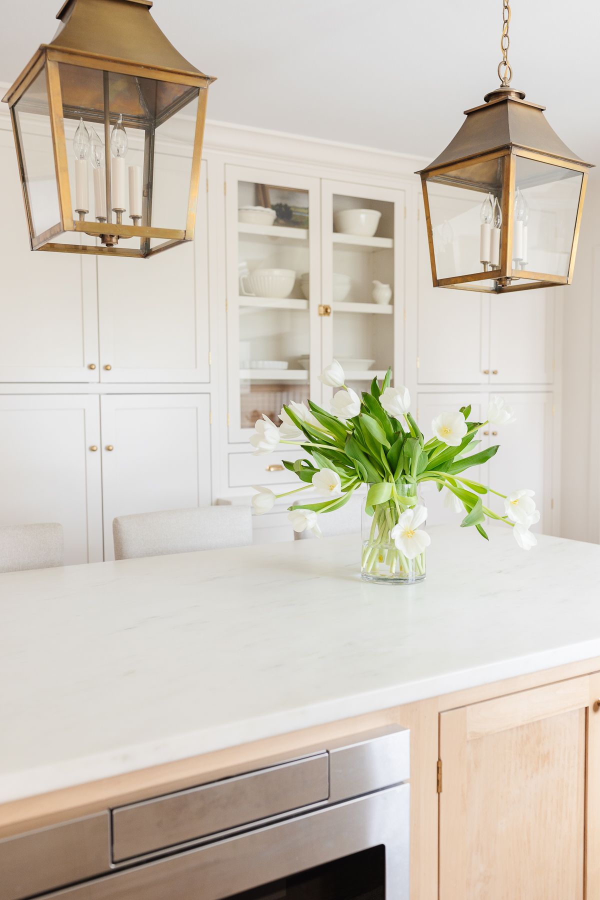 Two brass lantern pendants hanging over a kitchen island