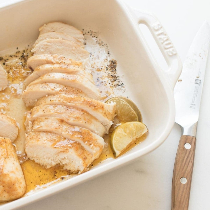oven baked chicken breast sliced in a white baking dish.