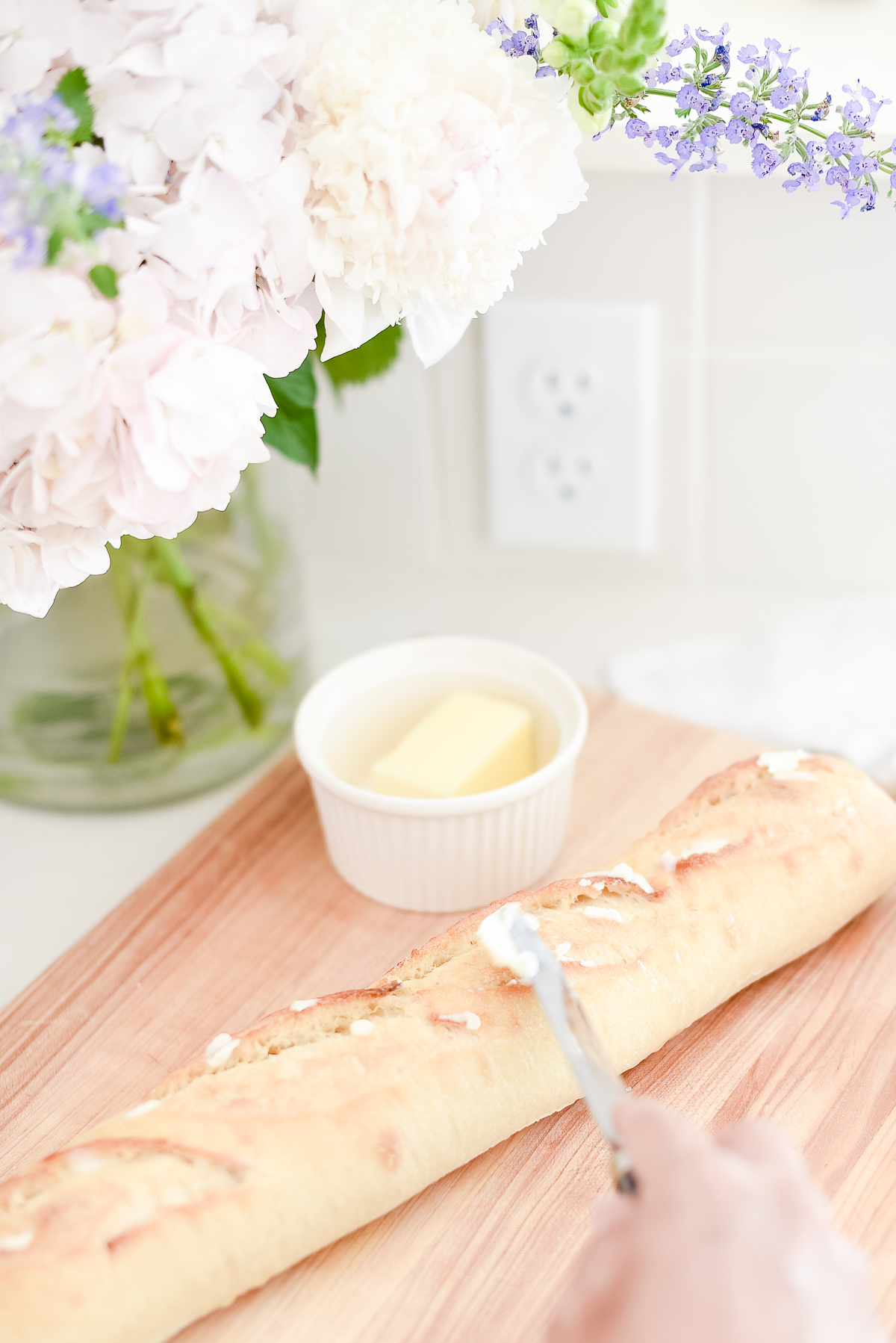 Bread for picnic sandwiches being sliced on a wooden cutting board.