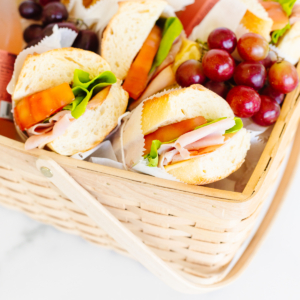 A picnic basket filled with sandwiches and grapes.
